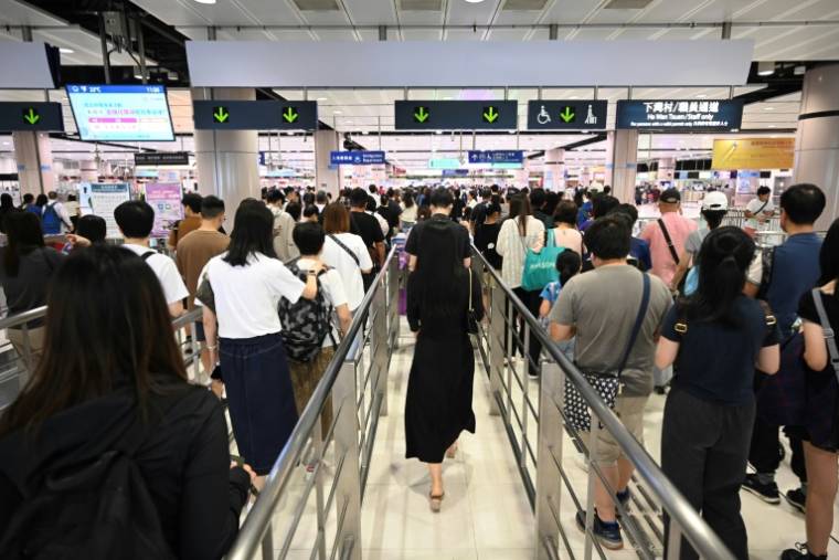 Des touristes de Hong Kong font la queue pour traverser la frontière vers Shenzhen au poste de contrôle de Lok Ma Chau, le 1er mai 2024 ( AFP / Peter PARKS )