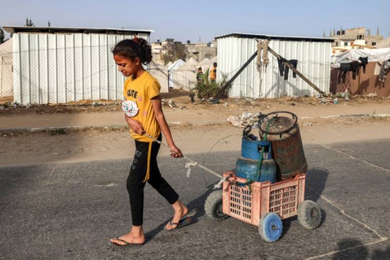 Une jeune fille tire un chariot chargé de bouteilles de gaz dans une rue de Rafah, dans le sud de la bande de Gaza, le 23 avril 2024 ( AFP / MOHAMMED ABED )