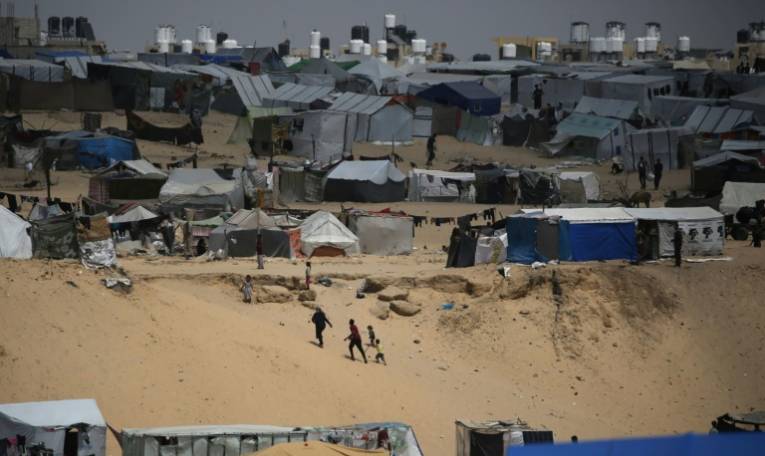 Des Palestiniens marchent dans un camp de personnes déplacées à Rafah, dans le sud de la bande de Gaza, près de la frontière avec l'Egypte, le 28 avril 2024 ( AFP / - )