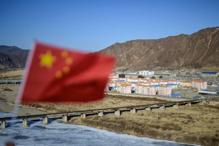 Un drapeau chinois et la ville nord-coréenne de Namyang en arrière-plan, près de la rivière Tumen, dans la province chinoise de Jilin, le 26 février 2024 ( AFP / Pedro PARDO )