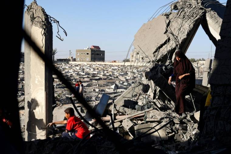 Une femme et des enfants palestiniens dans les décombres d'une maison touchée par des bombardements israéliens nocturnes à Rafah, dans le sud de la bande de Gaza, le 20 avril 2024 ( AFP / - )