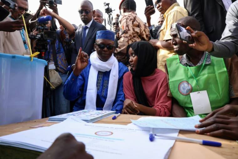 Le candidat à la présidentielle, Succès Masra (c) montre son doigt taché d'encre après avoir voté, le 6 mai 2024 à N'Djamena, au Tchad ( AFP / Joris Bolomey )