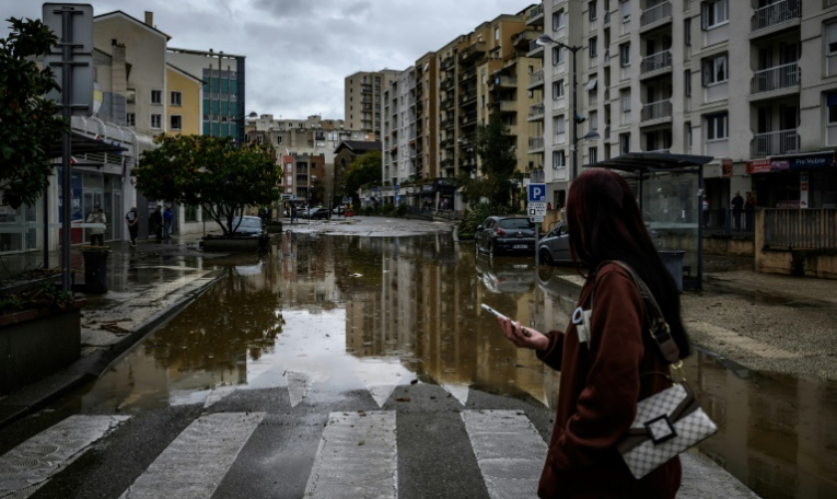 Une habitante passe dans une rue inondée d'Annonay, en Ardèche, le 17 octobre 2024 ( AFP / JEFF PACHOUD )