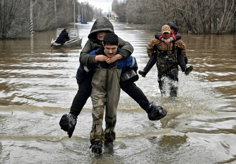 Des sauveteurs transportent sur leur dos des habitants d'une zone inondée à Orsk en Russie, le 8 avril 2024 ( Kommersant Photo / Anatoliy ZHDANOV )