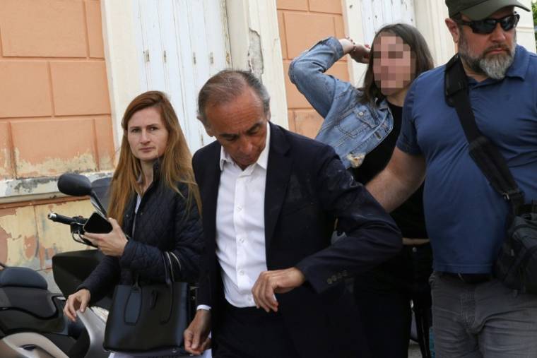 Une femme (D) jette un oeuf sur le président du parti d'extrême droite Reconquête! Éric Zemmour (G) lors d'une déambulation sur un marché, le 4 mai 2024 à Ajaccio  ( AFP / PASCAL POCHARD-CASABIANCA )