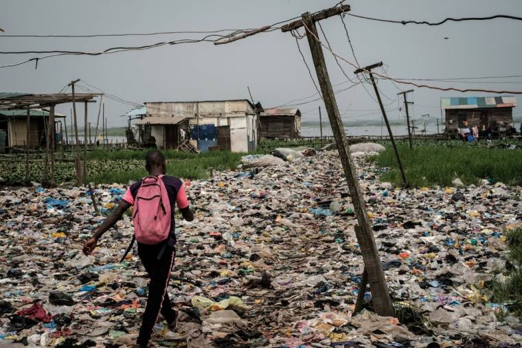 Un homme marche sur des déchets plastiques, dans la région de Mosafejo à Lagos (Nigeria) le 12 février 2019. Photo d'illustration.  ( AFP / YASUYOSHI CHIBA )