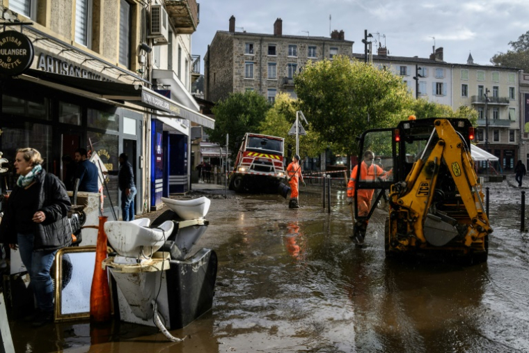 Un homme nettoie la boue et sort les meubles endommagés devant un magasinà Annonay,  en Ardèche, le 18 octobre 2024 ( AFP / JEFF PACHOUD )