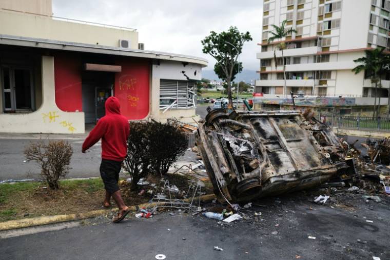 Un homme passe devant un véhicule brûlé lors d'un barrage routier indépendantiste dans le quartier de Magenta à Nouméa, en Nouvelle-Calédonie, territoire français du Pacifique, le 22 mai 2024 ( AFP / Theo Rouby )