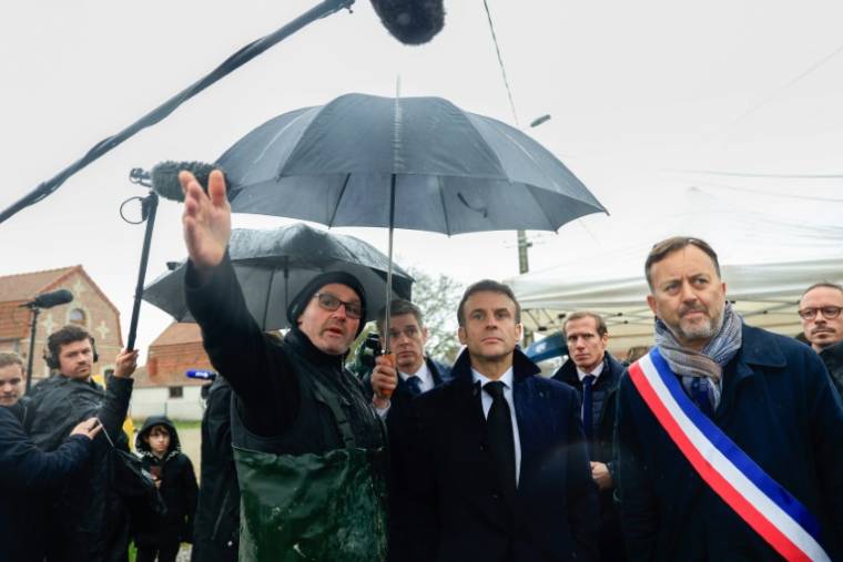 Le président Emmanuel Macron (c) écoute les explications d'un agriculteur, lors d'une visite à Le Doulac, près de Saint-Omer, dans le Pas-de-Calais touché par des inondations, le 14 novembre 2023 ( POOL / Aurelien Morissard )