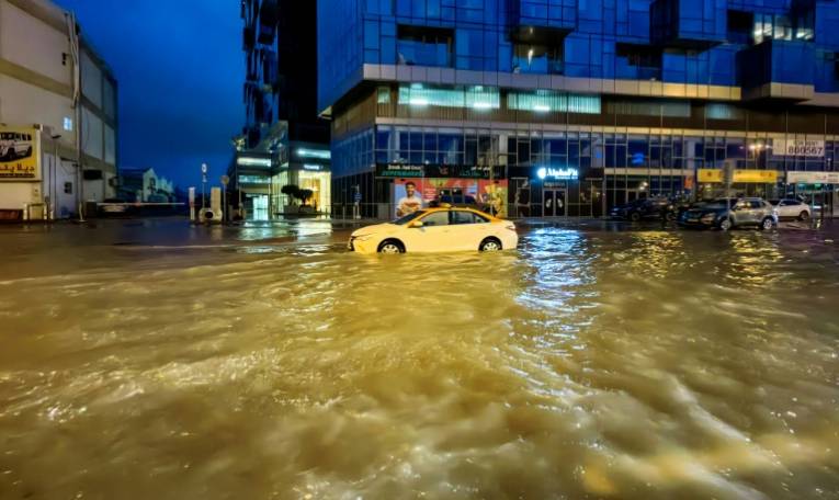 Un taxi traverse une rue inondée après des fortes pluies à Dubaï, le 17 avril 2024 ( AFP / Giuseppe CACACE )