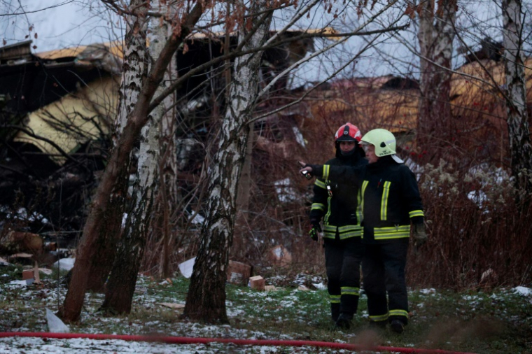 Des pompiers lituaniens travaillent à côté de l'épave d'un avion cargo qui s'est écrasé près de l'aéroport international de Vilnius, le 25 novembre 2024 ( AFP / Petras MALUKAS )