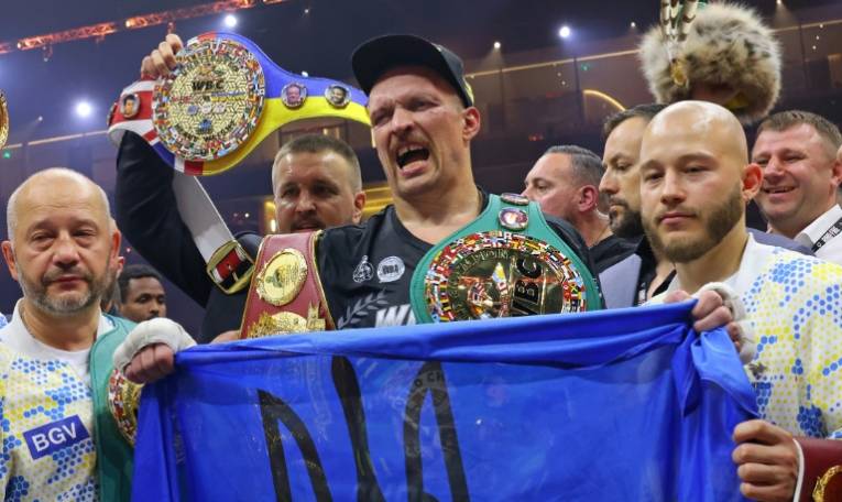 Oleksandr Usyk célèbre avec un drapeau ukrainien sa victoire sur Tyson Fury dans le championnat du monde des lourds à Riyadh, le 19 mai 2024. ( AFP / Fayez NURELDINE )
