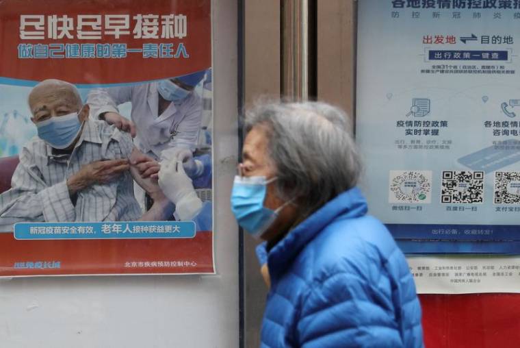 Photo d'archives d'une personne passant devant une affiche près d'un complexe résidentiel à Pékin