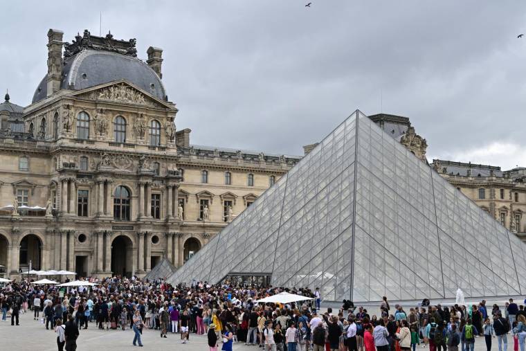 Les visiteurs font la queue pour entrer au Louvre, à Paris le 9 août 2023. ( AFP / MIGUEL MEDINA )