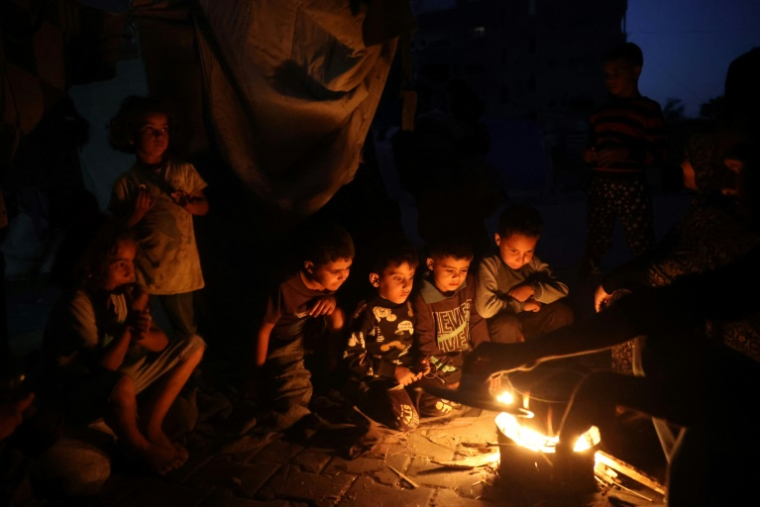 Des enfants palestiniens attendent de manger autour d'un feu dans le camp de réfugiés palestiniens de Bureij, dans le centre de la bande de Gaza, le 26 octobre 2024 ( AFP / Eyad BABA )