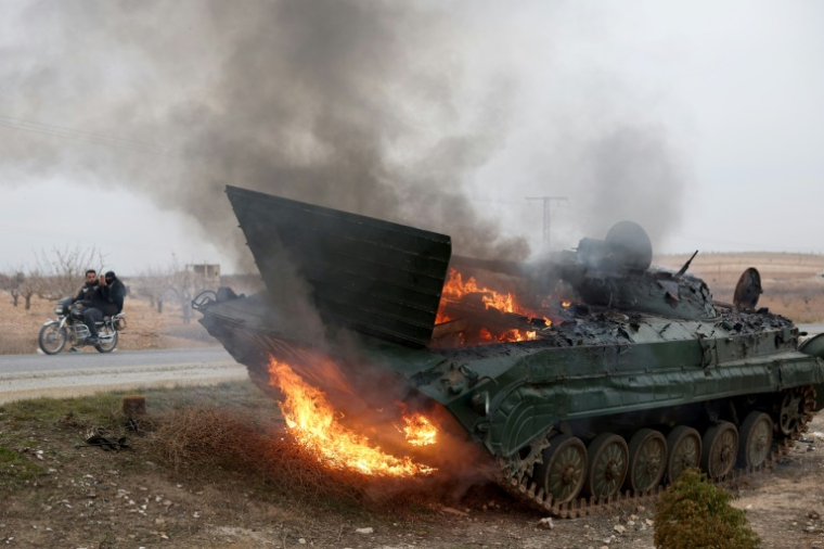 Un blindé de l'armée syrienne en feu dans la région de Hama, prise par les rebelles, le 7 décembre 2024 ( AFP / OMAR HAJ KADOUR )