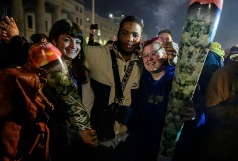 Des fumeurs de marijuana célèbrent la légalisation du cannabis récréatif en Allemagne, le 1er avril 2024 devant la porte de Brandebourg à Berlin ( AFP / John MACDOUGALL )
