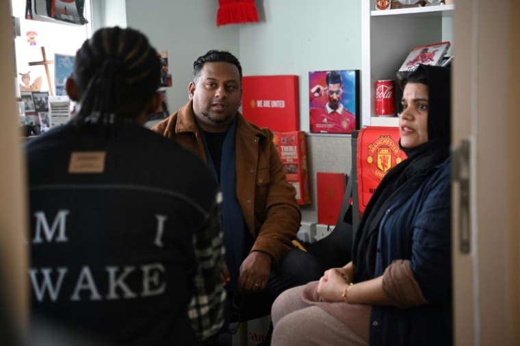 Uzma Naveed, coordinatrice, et Jeffrey Andrews, travailleur social, parlent à "John" dans un bureau de Centre d'action chrétien pour les réfugiés à Hong Kong ( AFP / Peter PARKS )