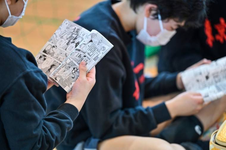 Des jeunes joueurs lisent le manga japonais de volley-ball "Haikyu!!" lors d'une pause pendant un entraînement dans un club de Tokyo, le 13 avril 2024 ( AFP / Richard A. Brooks )