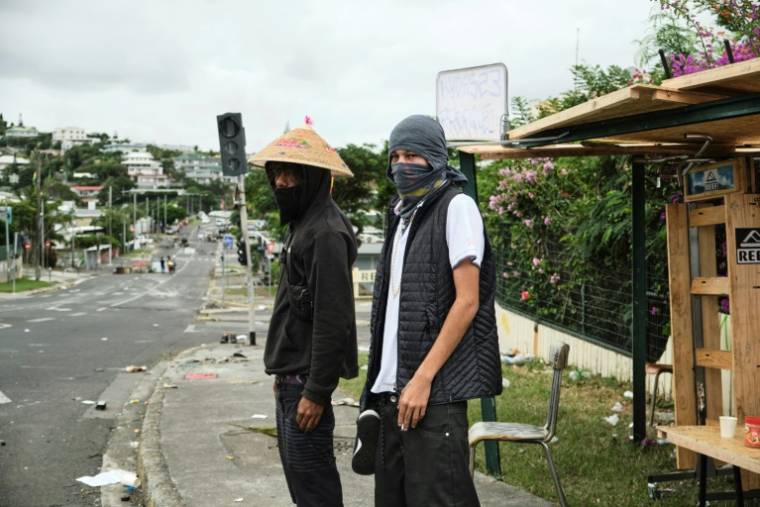 Deux manifestants devant un barrage indépendantiste dans le quartier de Magenta, à Nouméa, en Nouvelle-Calédonie, le 22 mai 2024 ( AFP / Theo Rouby )