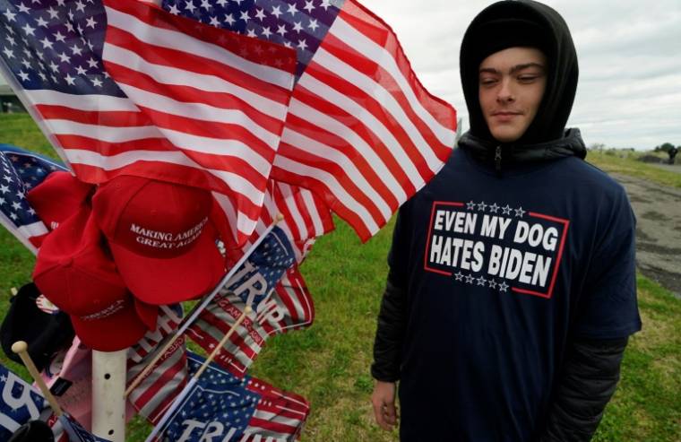 Un vendeur arbore un T-shirt "Même mon chien déteste Biden" avant un meeting de Donald Trump à Schnecksville, en Pennsylvanie, le 13 avril 2024 ( AFP / TIMOTHY A. CLARY )