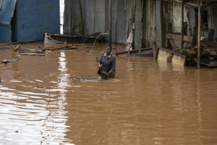 Les habitants du bidonville de Mathare traversent le quartier inondé à la suite de fortes pluies sur Nairobi, le 24 avril 2024 au Kenya ( AFP / SIMON MAINA )