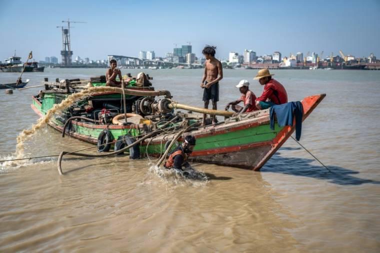 Des hommes récupèrent un navire coulé dans le fleuve Yangon, le 20 février 2024 à Rangoun, en Birmanie ( AFP / Sai Aung MAIN )