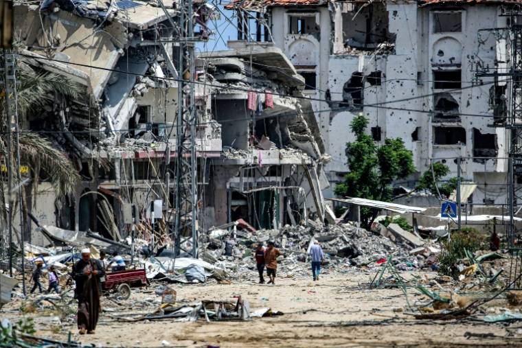 Des Palestiniens au milieu des décombres de bâtiments détruits à Khan Younès, dans le sud de la bande de Gaza, le 14 mai 2024 ( AFP / - )