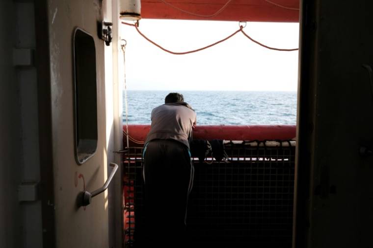 Un migrant bangladais observe le coucher du soleil depuis le pont principal du navire-ambulance Ocean Viking, le 21 mai 2024.  ( AFP / Clément MELKI )