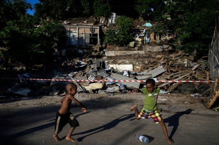 Des enfants jouent au football avec une bouteille en plastique devant les "cases" démolies du bidonville "Talus 2" à Koungou, sur l'île française de Mayotte, le 23 mai 2023 ( AFP / PHILIPPE LOPEZ )