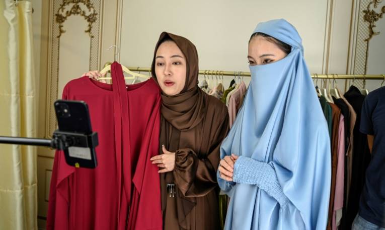 Des étudiantes chinoises en abayas font un live pour vendre des vêtements sur l'application TikTok, le 2 avril 2024 à Guangzhou, en Chine ( AFP / Jade GAO )