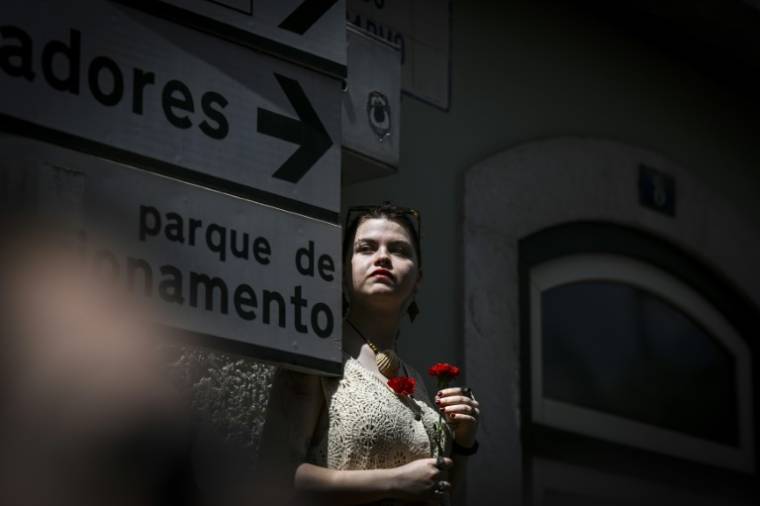 Une jeune femme tient des oeillets, symbole de la révolution du même nom, lors des célébrations le 25 avril 2024 à Lisbonne des 50 ans de la chute de la dictature au Portugal ( AFP / PATRICIA DE MELO MOREIRA )