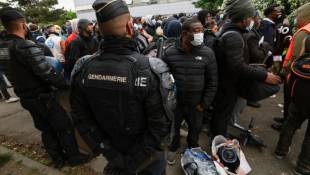 Des gendarmes encadrent des migrants lors de l'évacuation du plus grand squat de France, le 17 avril 2024 à Vitry-sur-Seine, dans le Val-de-Marne ( AFP / EMMANUEL DUNAND )