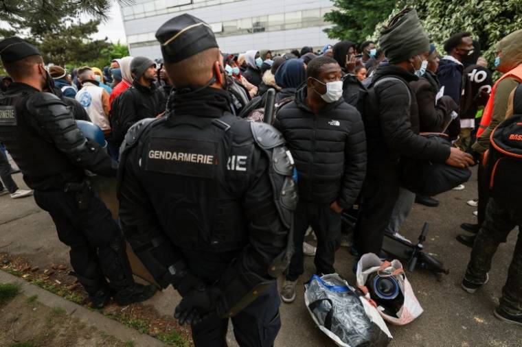 Des gendarmes encadrent des migrants lors de l'évacuation du plus grand squat de France, le 17 avril 2024 à Vitry-sur-Seine, dans le Val-de-Marne ( AFP / EMMANUEL DUNAND )