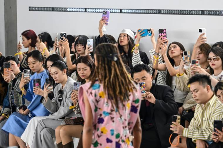 Des spectateurs prennent des photos du défilé "Voyager" de Louis Vuitton à Shanghai, le 18 avril 2024 ( AFP / Hector RETAMAL )
