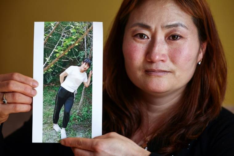 Kim Kyu-li montre une photo de sa soeur disparue, Kim Cheol Ok, lors d'un entretien à son domicile de Londres, le 25 mars 2024 ( AFP / Henry NICHOLLS )
