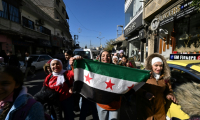 Des enfants syriens agitent le drapeau aux trois étoiles, symbole du soulèvement de 2011, à Damas le 15 décembre 2024 ( AFP / LOUAI BESHARA  )