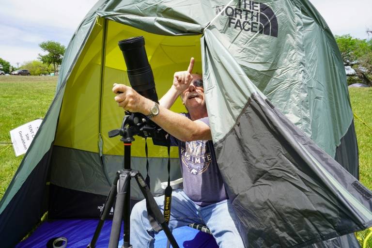Un campeur installé sous une tente au parc Stonehenge II, prépare son équipement photographique la veille de l'éclipse solaire totale de lundi en Amérique du Nord, le 7 avril 2024 à Ingram, au Texas  ( AFP / Cécile Clocheret )