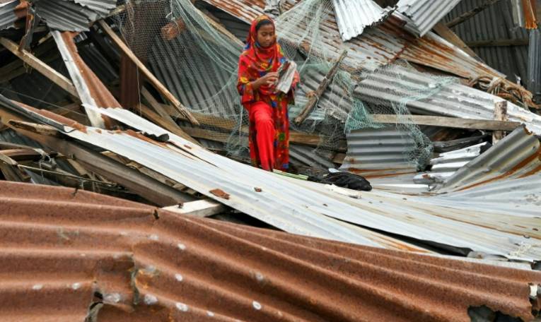 Une jeune fille parmi les débris de sa maison le 28 mai 2024 à Patuakhali au Bangladesh après le passage du cyclone Remal ( AFP / Munir Uz Zaman )