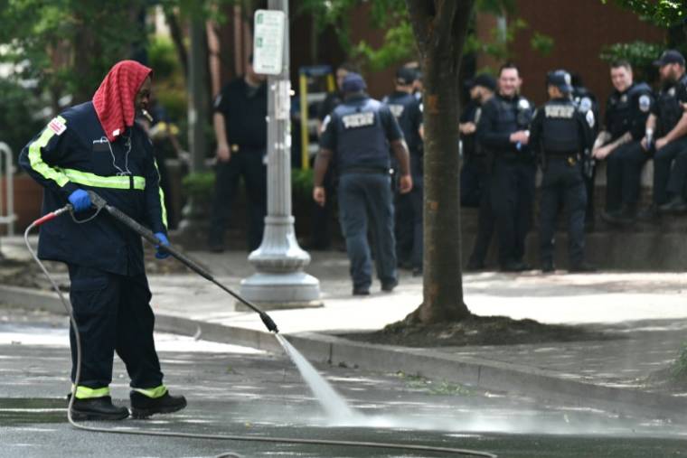 Un travailleur nettoie la rue après l'évacuation d'un campement propalestinien à l'université George Washington le 8 mai 2024 ( AFP / Brendan SMIALOWSKI )