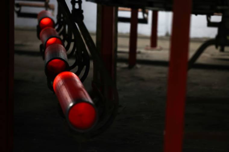 Des tubes d'acier incandescent, tout juste façonnés, refroidissent dans des petits paniers suspendus à un rail serpentant dans le sous-sol de l'usine de munitions de l'armée (SCAAP), à Scranton, le 16 avril 2024 en Pennsylvanie ( AFP / Charly TRIBALLEAU )