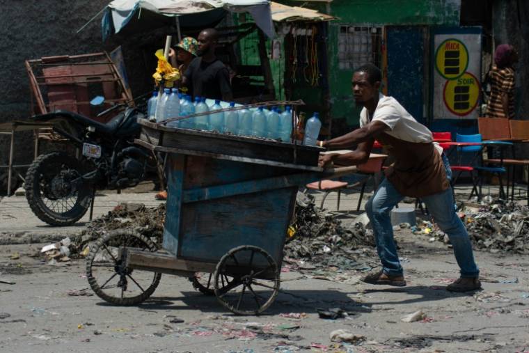 Un vendeur ambulant fuient la violence des gangs à Port-au-Prince, le 8 avril 2024 en Haïti ( AFP / Clarens SIFFROY )
