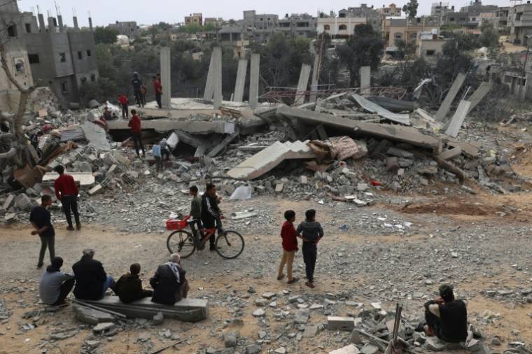 Des Palestiniens devant les décombres d'un bâtiment détruit par une frappe israélienne nocturne à Rafah, dans le sud de la bande de Gaza, le 29 mars 2024 ( AFP / SAID KHATIB )