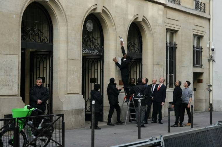 Un agent de sécurité retire une affiche à l'entrée de Sciences Po Paris, après que des étudiants ont pénétré à l'intérieur pour un rassemblement propalestinien, le 7 mai 2024 à Paris ( AFP / Dimitar DILKOFF )