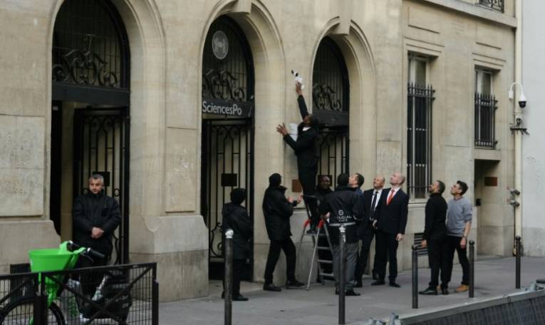 Un agent de sécurité retire une affiche de l'entrée de Sciences Po Paris, après que des étudiants ont pénétré à l'intérieur pour un rassemblement propalestinien, le 7 mai 2024 à Paris ( AFP / Dimitar DILKOFF )