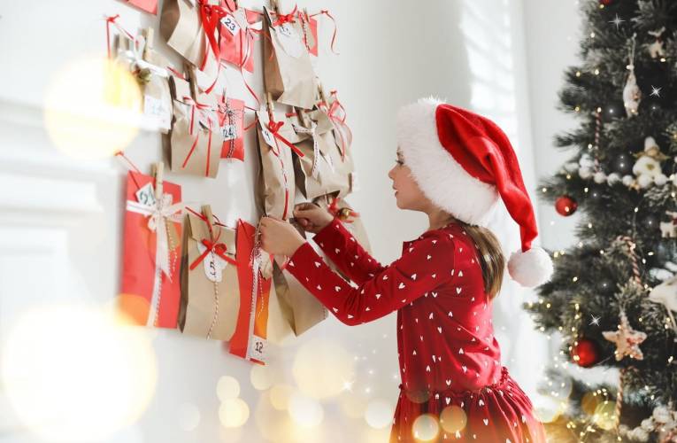 (Crédits photo : Adobe Stock - Petite fille en habit de Noël ouvrant une fenêtre du calendrier de l'Avent)