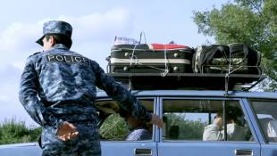 Un policier arménien fait signe à une voiture transportant des réfugiés d'entrer dans la ville de  Kornidzor frontière avec le Nagorny Karabakh, le 24 septembre 2023 ( AFP / ALAIN JOCARD )