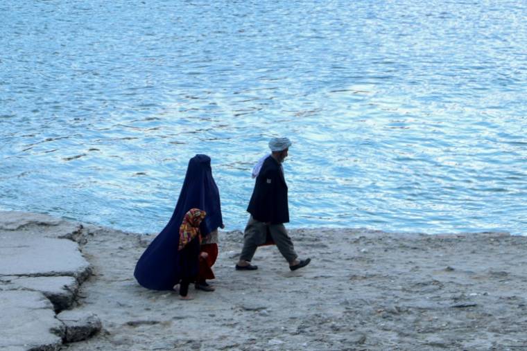 Une femme en burqa et une enfant suivent un homme le long de la rivière Kokcha à Fayzabad, dans la province du Badakhshan, le 14 février 2024 en Afghanistan ( AFP / OMER ABRAR )