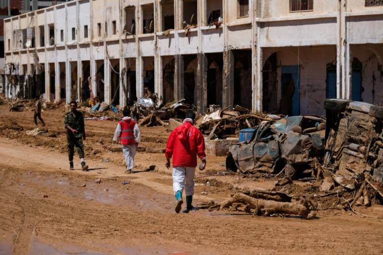 Des membres du Croissant Rouge marchent parmi des décombres à Derna en Libye