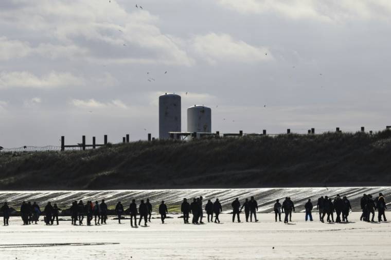 Des migrants sur la plage de Gravelines se dirigent vers un bateau de passeurs pour traverser la Manche, le 26 avril 2024 près de Dunkerque, dans le nord de la France ( AFP / Sameer Al-DOUMY )